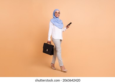 Full body photo of millennial arabic trend worker lady with bag telephone wear headscarf shirt eyewear trousers high heels isolated on beige background