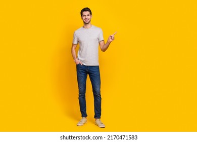 Full Body Photo Of Nice Brunet Millennial Guy Index Promo Wear T-shirt Jeans Sneakers Isolated On Yellow Background