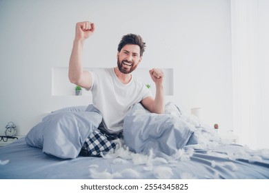 Full body photo of nice young man play fluffy bird feathers sit bed winning wear pajama wake up modern cozy interior bedroom indoors - Powered by Shutterstock