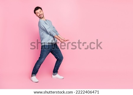 Full body photo of nice young man carry hold empty space banner toothy smiling wear stylish blue outfit isolated on pink color background