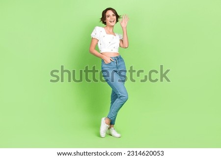 Full body photo of nice youngster lady see friends street say hi hey guys wear crop shirt jeans shoes isolated green color background