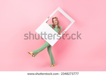 Full body photo of pretty young girl hold photo polaroid frame dance dressed stylish green print outfit isolated on pink color background