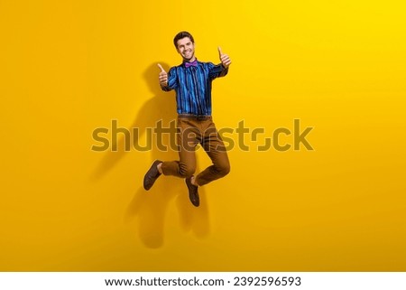 Full body photo of satisfied funky man wear bow tie stylish shirt jumping showing thumbs up to you isolated on yellow color background