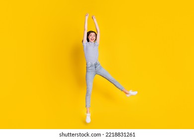 Full body photo of sporty young lady raise hands jump hang hold copyspace wear trendy striped clothes isolated on yellow color background - Shutterstock ID 2218831261