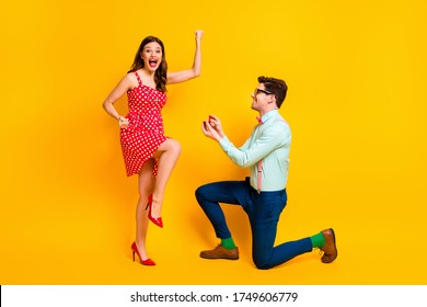 Full Body Photo Of Tow People Nerd Style Man Propose Girl Ecstatic Raise Fists Wear Red Dotted Dress High Heels Legs Mini Short Suspenders Pants Isolated Over Bright Shine Color Background