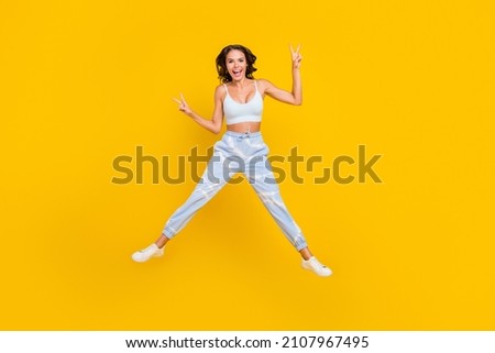 Full body photo of young active girl jump up show finger peace v-symbol isolated over yellow color background