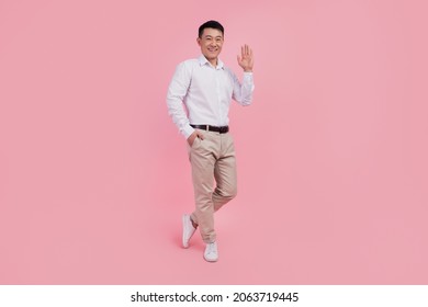 Full Body Photo Of Young Asian Man Waving Hand Hello Greeting Friendly Isolated Over Pink Color Background