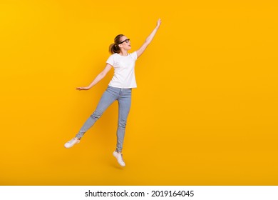 Full body photo of young attractive woman happy positive smile jump try to catch umbrella isolated over yellow color background