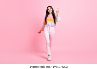 Full body photo of young cheerful girl happy positive smile show peace cool v-sign go walk step isolated over pink color background