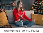 Full body photo of young girl sit sofa meditate wear red christmas clothes enjoy modern cozy x-mas party decoration interior flat indoors