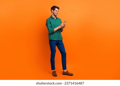 Full body photo of young guy worker hr manager recruiter browsing swipe internet web pages smartphone isolated on orange color background - Powered by Shutterstock