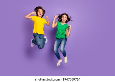 Full body photo of young kids happy smile jump up celebrate win victory success fists hands isolated over purple color background