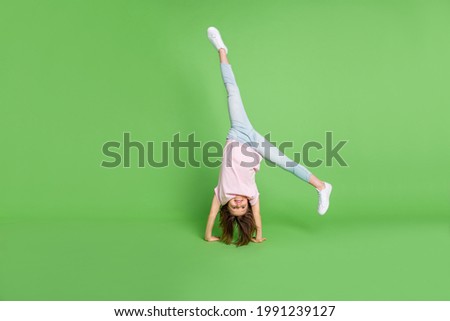 Full body photo of young little girl stand on hand acrobat sporty training isolated over green color background