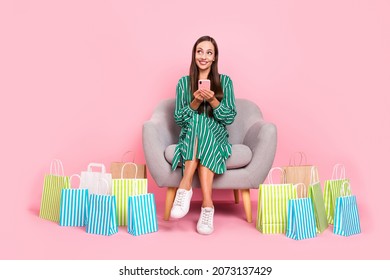 Full body photo of young wondered lady look empty space use cellphone shop order sit stool isolated over pastel color background