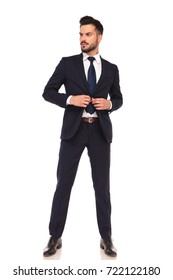 Full Body Picture Of Confident Young Business Man Buttoning His Suit And Looks Away To A Side On White Background