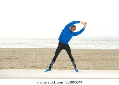 Full body portrait of african american man stretching muscles at the beach  - Powered by Shutterstock