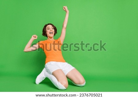 Full body portrait of astonished lady open mouth stand on knees slide look empty space isolated on green color background