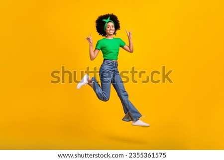 Full body portrait of beautiful excited teen schoolgirl jump hands fingers show heavy metal symbol isolated on yellow color background