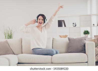 Full body portrait of carefree cheerful person sit on sofa closed eyes open mouth smile raise arm weekend indoors - Shutterstock ID 1925089220