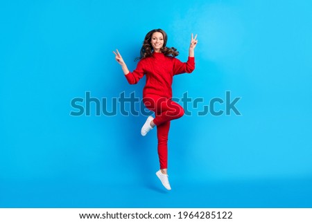 Full body portrait of carefree cheerful girl toothy smile fingers show v-sign isolated on blue color background