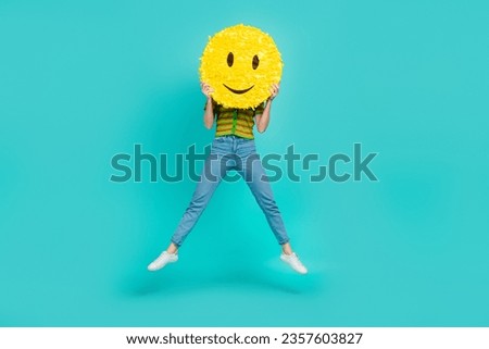 Full body portrait of carefree crazy lady jumping arms hold big smiley emoji isolated on turquoise color background
