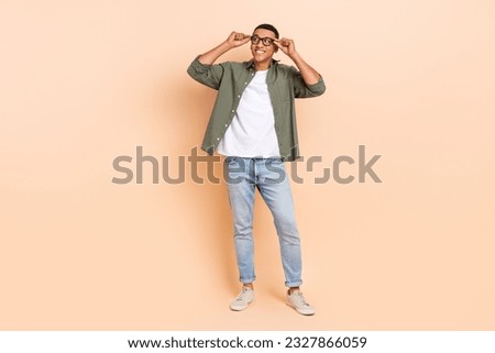 Full body portrait of cheerful minded creative person arms touch eyewear look empty space isolated on beige color background