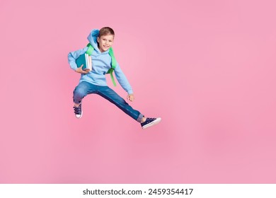 Full body portrait of energetic little schoolkid hold book backpack jump empty space isolated on pink color background - Powered by Shutterstock