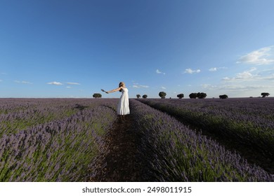 Full body portrait of an excited woman outstretching arms celebrating in lavender field - Powered by Shutterstock