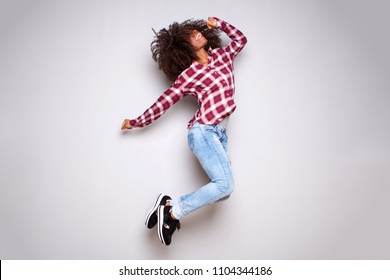 Full body portrait of excited young woman jumping in air against white background