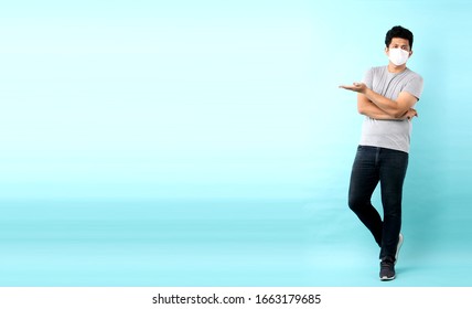 Full body Portrait of handsome Asian man wearing a mask is sick Pointing finger isolated on blue background in studio With copy space. - Powered by Shutterstock