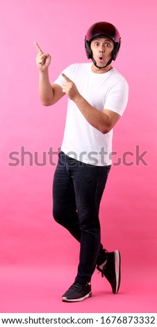 Full body Portrait of handsome Asian man wearing a helmet motor and Pointing finger on empty space.on pink background in studio. 