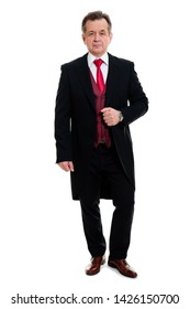 Full Body Portrait Of Handsome Confident Caucasian Mature Businessman 55-60 Years Old In Black Tuxedo And Red Vest Standing And Looking To Camera On Isolated White Background.