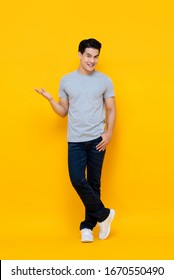 Full Body Portrait Of Handsome Young Asian Man Smiling And Standing With Open Hand Gesture Isolated On Yellow Background