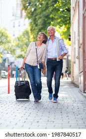 Full Body Portrait Happy Older Couple Walking With Suitcase On Street