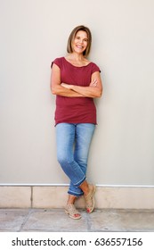 Full Body Portrait Of Happy Older Woman Leaning Against Wall