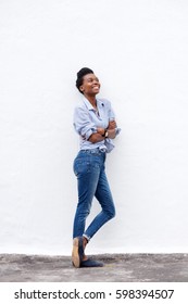 Full Body Portrait Of Happy Young Black Woman Leaning Against Wall Looking Up