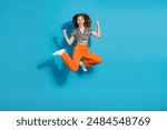 Full body portrait of lovely young girl jump raise fists wear top isolated on blue color background