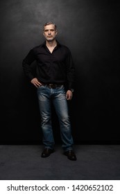 Full Body Portrait Of Middle-aged Good Looking Man Posing In Front Of A Black Background With Copy Space