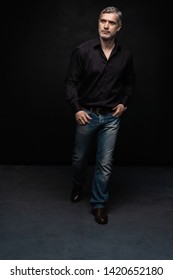 Full Body Portrait Of Middle-aged Good Looking Man Posing In Front Of A Black Background With Copy Space