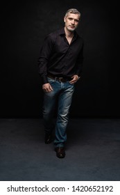 Full Body Portrait Of Middle-aged Good Looking Man Posing In Front Of A Black Background With Copy Space