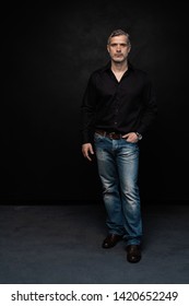 Full Body Portrait Of Middle-aged Good Looking Man Posing In Front Of A Black Background With Copy Space