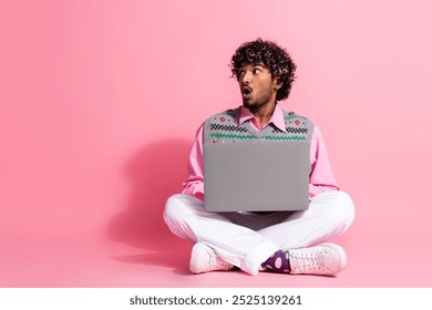 Full body portrait of nice young man sit floor laptop look empty space wear xmas new year vest isolated on pink color background - Powered by Shutterstock