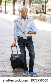 Full Body Portrait Older Man Standing In City With Mobile Phone And Suitcase