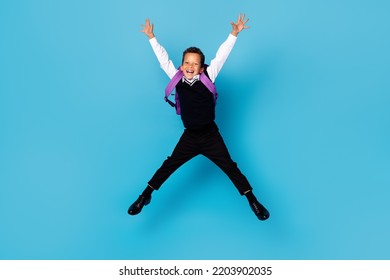 Full body portrait of overjoyed carefree boy jumping raise hands make star figure isolated on blue color background - Shutterstock ID 2203902035