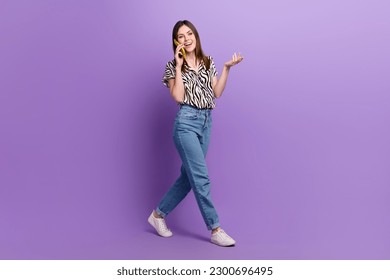 Full body portrait of positive nice lady walking speak communicate telephone isolated on purple color background - Powered by Shutterstock