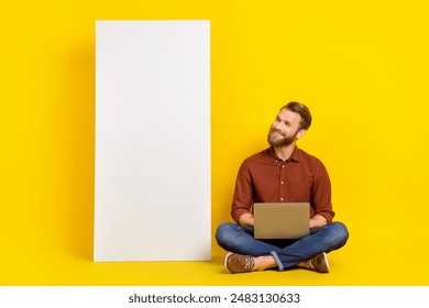 Full body portrait of positive person sit floor use netbook use empty space banner isolated on yellow color background - Powered by Shutterstock