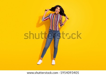 Full body portrait of pretty cheerful dark skin lady hands hold play with hair isolated on yellow color background
