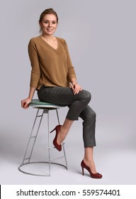 full body portrait of a pretty smiling woman sits on chair