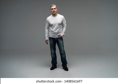 Full Body Portrait Of Relaxed Mature Man Standing Over Gray Background