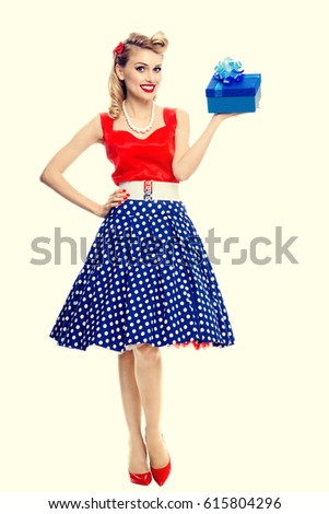 Full body portrait of smiling woman dressed in pin-up style dress with polka dot. Caucasian blond model posing in retro fashion and vintage concept studio shoot.